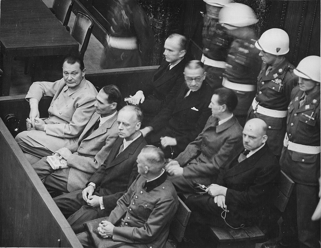 Lavice obžalovaných – Přední řada: Göring, Hess, von Ribbentrop a Keitel. Druhá řada: Dönitz, Raeder, Schirach a Sauckel.