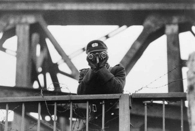 Východoněmecká stráž VOPO hlídá jeden z mostů spojujících Východní a Západní Berlín v roce 1961. https://rarehistoricalphotos.com/berlin-wall-pictures-1961-1989